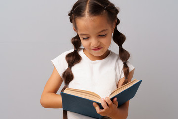 Little  girl  holding a book in her hands over a grey background