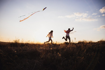 Young couple have fun with kite. they send Genuine emotions  to the world.