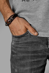 Cropped close-up shot of a male wrist with a multilayer leather bracelet made of leather braids and...