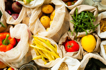 fresh vegetables in eco cotton bags on table top view