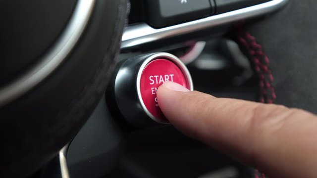 Finger pushing start engine button in a sports car close up