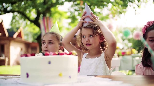 A birthday party of small girl outdoors in garden in summer, celebration concept.