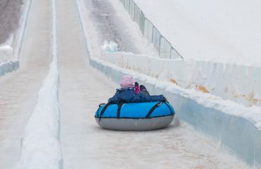 a child descends from a winter ice slide in a sleigh