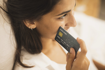 Close-up woman holding a credit card next to her cheek