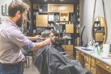 Barbershop. Hairdresser does hairstyle with hair clipper and comb.