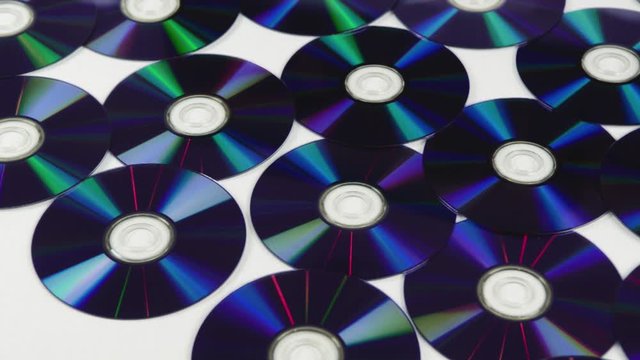 Blue CDs BlueRay DVDs isolated on a white background pan from left to right