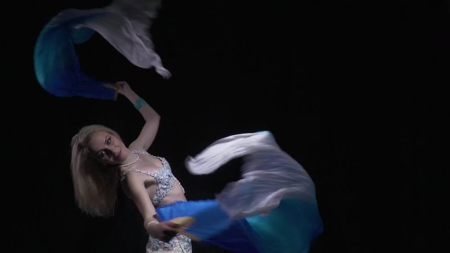 Woman is holding two fans with cloth on them, arching her back swinging them