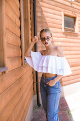 Attractive young girl with a perfect figure and blond hair in trendy jeans and a white top with...