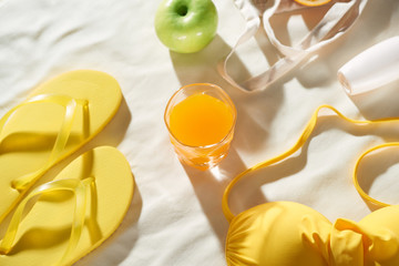 Summertime picnic on white background with fruit bag, flip-flop, sin cream and juice, flat lay