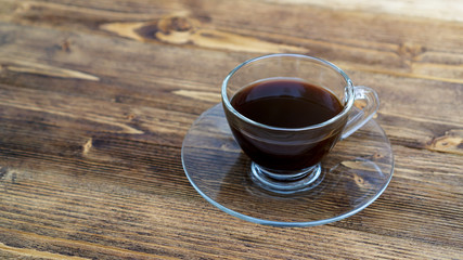 A cup of hot black coffee on a wooden table.