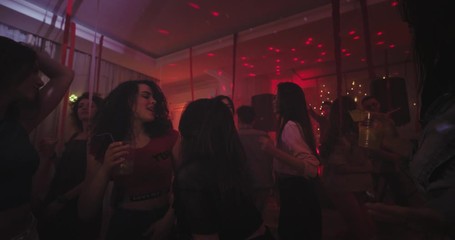 Big home party lots of young ladies and guys dancing and chilling out in a large spacious living room