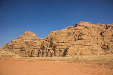 Fototapeta na wymiar planet Earth world heritage touristic destination site Wadi Rum Jordan Middle East scenery landscape view sand valley foreground and picturesque mountain ridge on blue sky background 