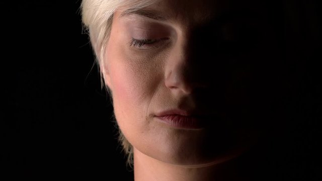 Woman looks intensely at camera into the dark. Dramatic close-up