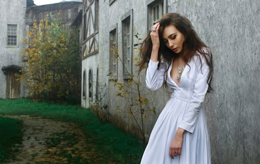 Young beautiful mysterious girl in white dress in old medieval town