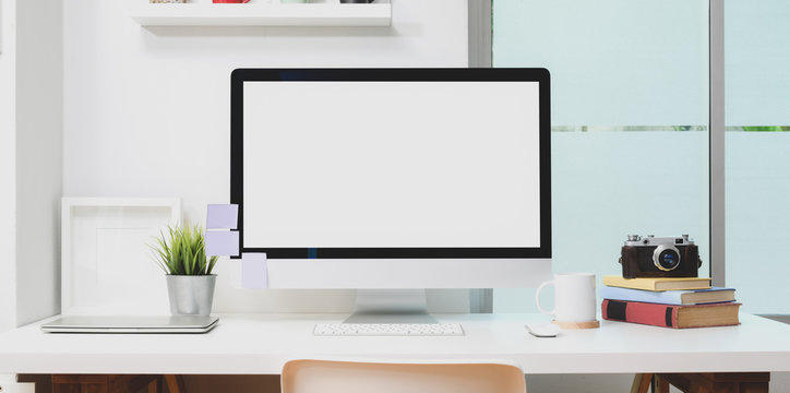 Blank screen desktop computer with office supplies and mock up frame in modern workplace