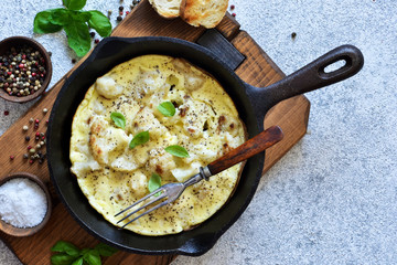 Omelet with vegetables in a pan on a concrete background. View from above.