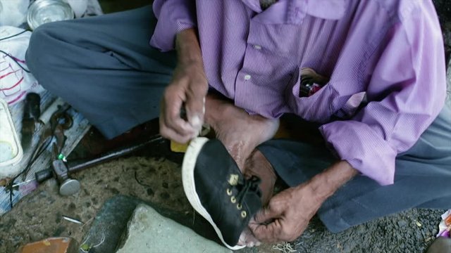 A cobbler repairing slippers of pilgrims by the roadside in the morning stock footage collection 4