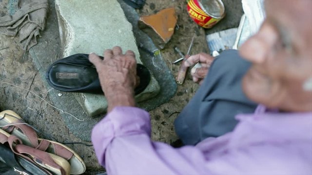 A cobbler repairing slippers of pilgrims by the roadside in the morning stock footage collection 21