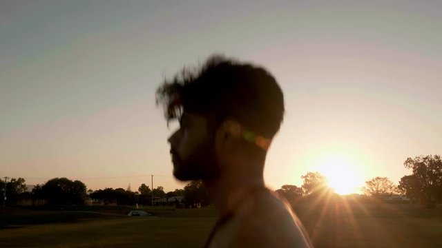 Indian guy running and trainning for cardio exercise on public park during sunset.