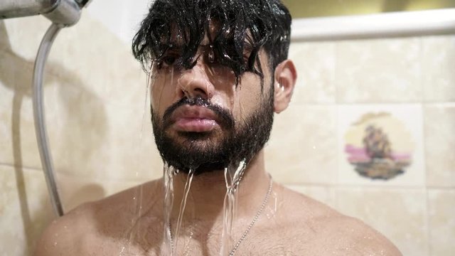 Indian guy taking shower in shower booth after stressful day