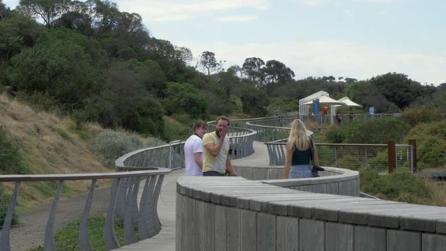 Family walking wooden boardwalk. Male smacks female buttocks, female responds with slap to mans face. Cheeky funny relationship humour.