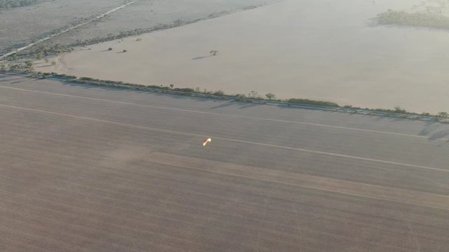 Nice view of powered paragliding flying over the broad drout empty crop field