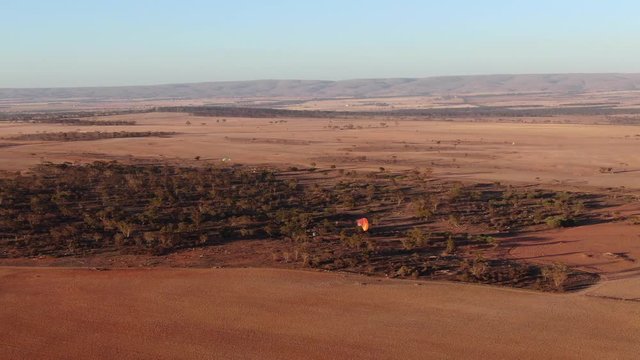 Aerial drone view of paramotor having fun gliding and flying in the air over a nice wide field