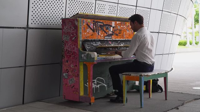 Man plays on colorful piano at Dongdaemun design plaza in seoul. Tripod shot.