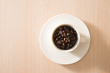 Cup of full coffee beans on the wood background