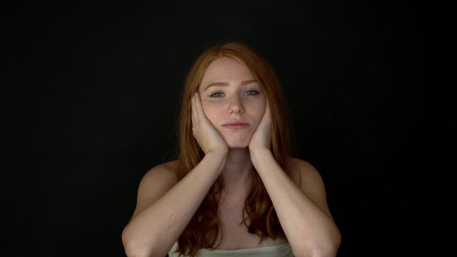 Bored redhead woman looking at camera. She is disappointed and fatigue.