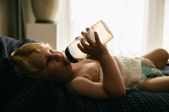 Kleiner Junge trinkt Milch aus einer Flasche