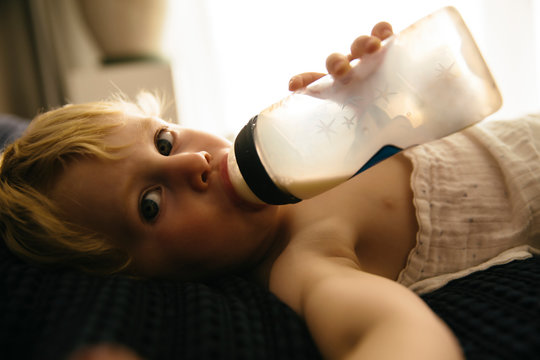 Kleiner Junge trinkt Milch aus einer Flasche