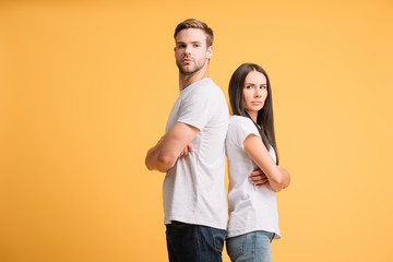 offended couple standing with crossed arms, isolated on yellow