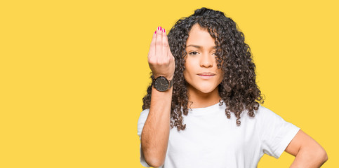 Young beautiful woman with curly hair wearing white t-shirt Doing Italian gesture with hand and fingers confident expression