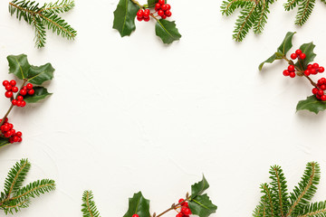 Christmas background with branches of fir tree, evergreens and holly with red berries on white. Winter nature concept. Flat lay, copy space.