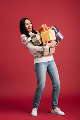 beautiful excited woman holding christmas presents isolated on red