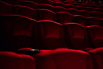 empty red velvet seats in cinema auditorium .