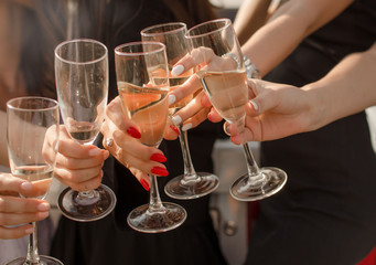 The company of people celebrates the New Year fun. Champagne in glasses and fun at a girls party. Cheerful bachelorette party in a noisy company. Photo in warm colors.