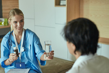 Beautiful smiling woman the doctor in a bottle of pill offers the patient