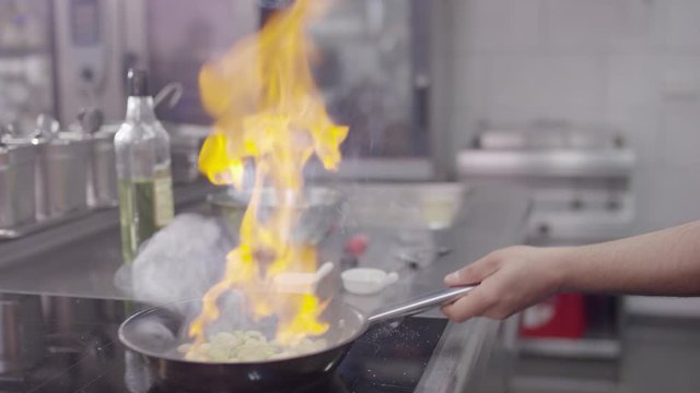 Vegetables being flamb&eacute;red in a clean and modern hotel kitchen by a cook - Gem&uuml;se, das von einem Koch in einer sauberen und modernen Hotelk&uuml;che flambiert wi