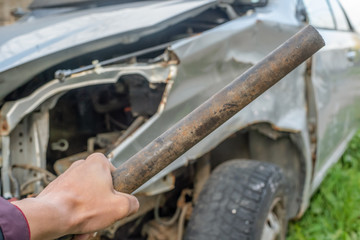 Fototapeta premium Hand with a metal bat on the background of the car. Aggression towards drivers