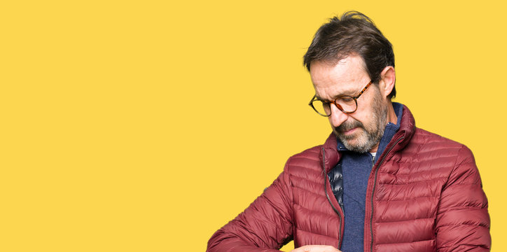 Middle age handsome man wearing glasses and winter coat Checking the time on wrist watch, relaxed and confident