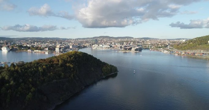 Cinema 4K drone shot with forward tilt reveal motion of Hoved&oslash;ya island, the blue Oslofjord and the Bj&oslash;rvika project with the Lambda Edvard Munch Museum and Opera House in autumn fall, in Oslo Norway.