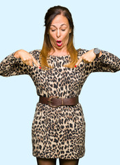 Beautiful middle age woman wearing leopard animal print dress Pointing down with fingers showing advertisement, surprised face and open mouth
