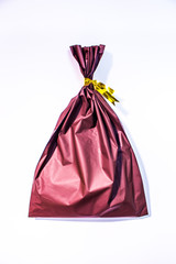 Small wrapped bag with gift. The bag in image is tied with golden ribbons, isolated on white background.