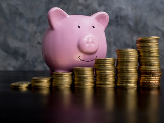pink piggy bank with growth coins bar graph on black cement wall background, Saving money for future plan and retirement fund concept