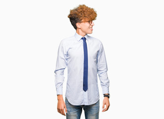 Fototapeta premium Young handsome business man with afro wearing glasses looking away to side with smile on face, natural expression. Laughing confident.