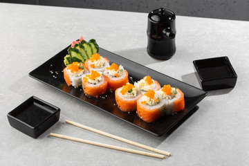 Philadelphia roll sushi with salmon, avocado, cream cheese and red caviar. Sushi menu. on dark plate. Traditional japanese seafood, healthy food concept. Top view horizontal photo on white background.