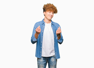 Young handsome man with afro hair wearing denim jacket Doing money gesture with hand, asking for salary payment, millionaire business