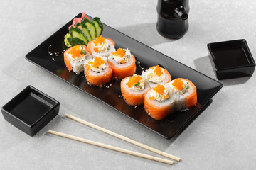 Philadelphia roll sushi with salmon, avocado, cream cheese and red caviar. Sushi menu. on dark plate. Traditional japanese seafood, healthy food concept. Top view horizontal photo on white background.